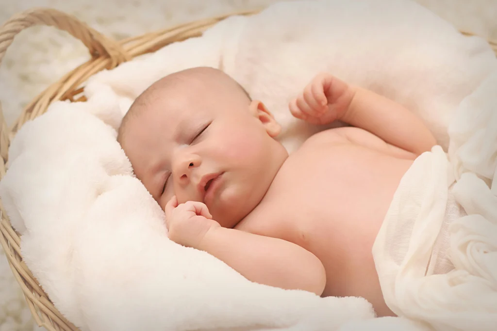 baby sleeping in white swaddle